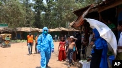 Seorang pekerja kesehatan dari sebuah organisasi bantuan berjalan mengenakan jas hazmat di kamp pengungsi Kutupalong Rohingya di Cox's Bazar, Bangladesh, 15 April 2020. (Foto: AP)