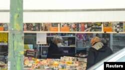 이탈리아 정부가 전국에 이동제한령을 내린 가운데 한 마스크를 한 상인이 손님에게 신문을 전하고 있다.