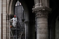 A worker stands on scaffolding during preliminary work inside the Notre Dame de Paris Cathedral, May 15, 2019, in Paris.