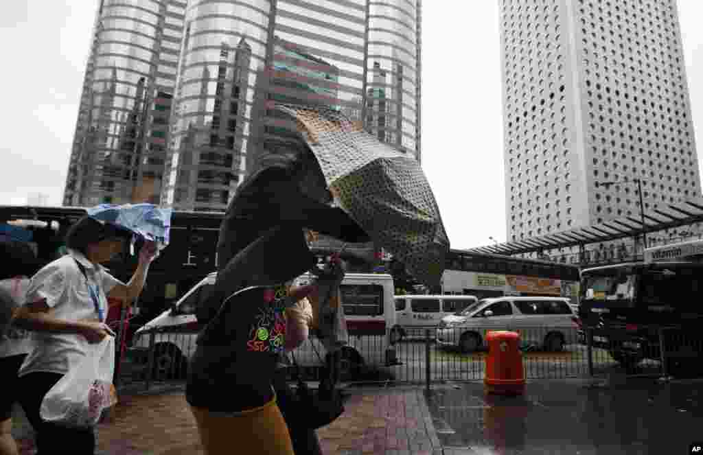 Pedestrians brave the strong winds in Central, the business center in Hong Kong Monday, July 23, 2012. 
