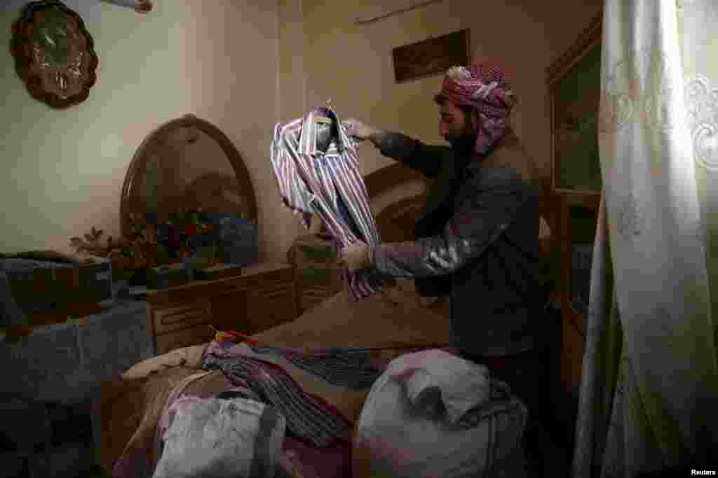 A man inspects a shirt of his dead son, who died in an airstrike in the rebel-held besieged city of Douma, a suburb of Damascus, Syria, Feb. 27, 2016.