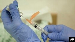 FILE - A nurse practitioner prepares a flu vaccination in Rockville, Maryland, Aug. 27, 2010. 