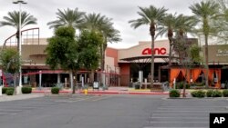 An empty parking lot leading to a closed AMC movie theatre and restaurants sits idly March 18, 2020, in Phoenix.