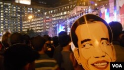 Salah seorang pengunjung Jakarta Night Festival mengenakan topeng Gubernur Joko Widodo (31/12) pada perayaan malam tahun baru di Bundaran HI. (VOA/Andylala Waluyo)