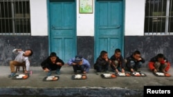 Học sinh ăn trưa ngoài trời tại trường tiểu học ở làng Đồng Quan, tỉnh Quý Châu ở Trung Quốc.