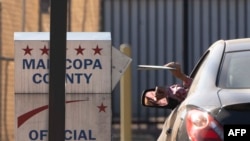 Glasači ubacuju glasačke listiće u kutiju ispred Centra za izbore u okrugu Marikopa u Finiksu, Arizona, 19. oktobar, 2024.(Foto: AFP/Rebecca Noble)