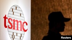 Seorang petugas keamanan berdiri di dekat logo Taiwan Semiconductor Manufacturing Co. Ltd (TSMC) di Taipei. (Foto: REUTERS/Pichi Chuang)