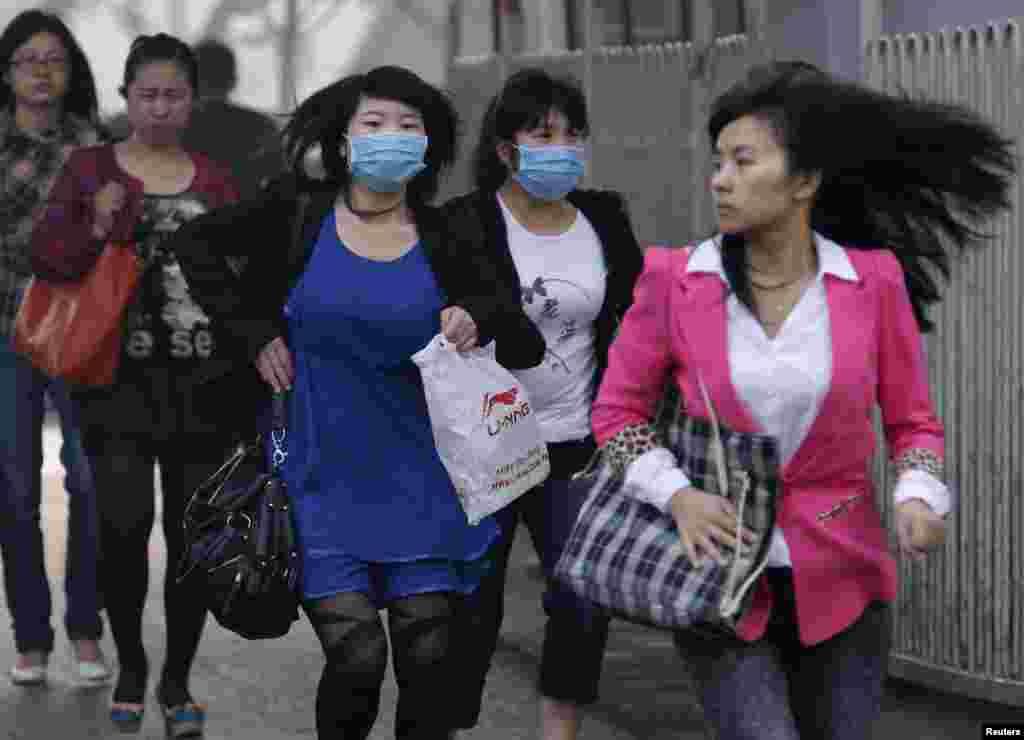 Women wearing face masks run to cross a street in Beijing, May 6, 2013. The United States Embassy monitor on air quality in China classified the quality of air in Beijing as &quot;hazardous.&quot;