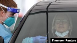 File: A medical worker swabs a member of the public at a drive-through COVID-19 testing centre in Sydney, Australia.