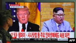 Seorang tentara Korea Selatan berjalan melewati layar televisi saat menayangkan gambar Presiden AS Donald Trump (kiri) dan pemimpin Korea Utara Kim Jong-un di sebuah stasiun kereata api di Seoul, 9 Maret 2018. (Foto: dok).