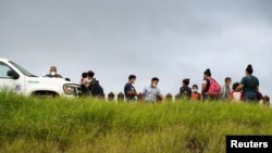 FILE - Asylum-seeking migrants from Central America are processed by U.S. Border Patrol agents after crossing the Rio Grande into the United States from Mexico, in Penitas, Texas, July 8, 2021.
