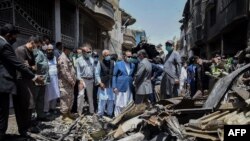 In this picture taken on May 23, 2020, and released by Pakistan's Civil Aviation Authority (PCAA), Pakistani officials inspect the site a day after a Pakistan International Airlines passenger plane crashed in a residential area in Karachi. 