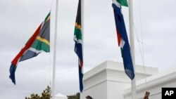 A policeman adjusts South African flags to half-mast outside parliament in Cape Town, South Africa, Nov. 25, 2020.