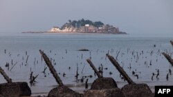 Ova slika snimljena 5. decembra 2023. prikazuje tajvansko udaljeno ostrvo Shihyu, kako se vidi iza šiljaka protiv slijetanja na tajvanskom ostrvu Little Kinmen na liniji fronta.