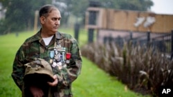 Argentine war veteran Jorge Altieri stands for a picture with the blood-stained helmet that saved his life in 1982 during the Falklands war, in Buenos Aires, Argentina. (AP Photo/Natacha Pisarenko)