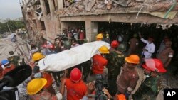 Bangladeshi rescue workers carry the body of a dead garment worker after it was retrieved from a building that collapsed on Wednesday in Savar, near Dhaka, Bangladesh, April 28, 2013.