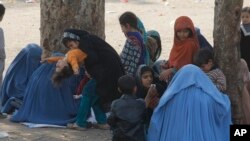 Afghan refugee families sit outside the government registration office preparing to leave for their homeland, in Peshawar, Pakistan, March 14, 2017.