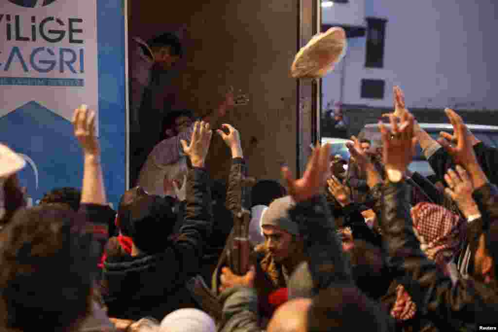 People gather to receive flatbread after rebels seized the capital and ousted Syrian President Bashar al-Assad, in Damascus.
