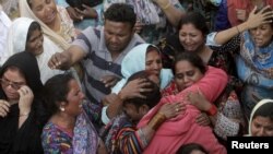 Des membres d'une famille lors des obsèques, lundi, d'une des victimes de l'attentat de Lahore au Pakistan. 