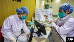 This photo taken on January 30, 2020 shows medical staff members wearing face masks talking at a hospital in Wuhan in China's central Hubei province.