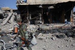 FILE - A Kurdish fighter walks past a destroyed building in the town of Sinjar on Nov. 13, 2015, after they took it from the Islamic State group in a joint operation with the coalition forces.