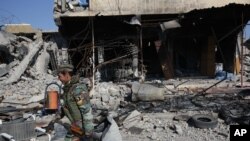 A Kurdish fighter walks past a destroyed building in the town of Sinjar on Nov. 13, 2015 after they took it from the Islamic State group in a joint operation with the coalition forces. 
