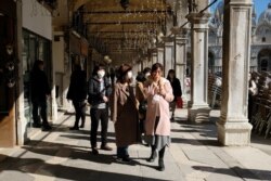Tourists wearing protective masks walk through Saint Mark's Square in Venice, Italy, Feb. 27, 2020.