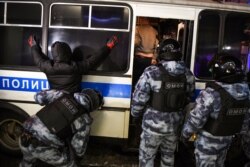FILE - A riot police officer searches a detained man during a protest against a court ruling ordering Russian opposition leader Alexey Navalny jailed for nearly three years, in downtown Moscow, Feb. 3, 2021.