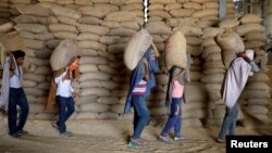 FILE - Workers carry bags of wheat for sorting at a wheat processing center, or grain mill, outside of Ahmedabad, India on May 16, 2022. (REUTERS/Amit Dave/File Photo)
