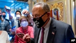 Senate Majority Leader Chuck Schumer of New York walks out of a Senate Democratic meeting pumping his fist, at the Capitol in Washington, Oct. 6, 2021, as a showdown loomed with Republicans over raising the debt limit.