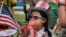 FILE - Eight year old Hana Cho from Girl Scout Troop 5665 tests out a horn prior to participating the 4th of July parade in Santa Monica, Calif. on Tuesday, July 4, 2017.