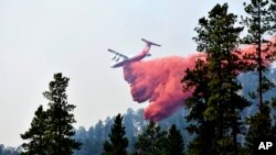 FILE - An aircraft drops fire retardant to slow the spread of the Richard Spring fire, east of Lame Deer, Montana, on Aug. 11, 2021.