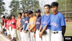 យុវជន​កម្ពុជា​ឈរជា​ជួរ​ដើម្បី​ត្រៀម​ចូល​លេង​កីឡា​បេស្បល​នៅ​ទីលាន​មួយ​ក្នុង​ឃុំបល្ល័ង ភូមិ​ដូង​​ស្រុក​បារាយណ៍ ខេត្ត​កំពង់​ធំកាលពី​ថ្ងៃទី​១៨ មីនា ឆ្នាំ២០១៨។(ទុំ ម្លិះ/VOA)