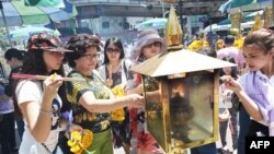 FILE - Women light incense sticks before offering prayers at the reopened Erawan Shrine, the popular tourist site where 20 people were killed on August 17 in a bomb blast in Bangkok, Aug. 20, 2015. 