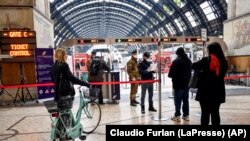 ប៉ូលិស និង​ទាហាន​ត្រួតពិនិត្យ​អ្នក​ដំណើរ​ដែល​ចាកចេញ​ពី​ស្ថានីយ​រថភ្លើង​ដ៏​សំខាន់​មួយ​ក្នុង​ក្រុង Milan ប្រទេស​អ៊ីតាលី កាលពី​ថ្ងៃទី៩ ខែមីនា ឆ្នាំ២០២០។