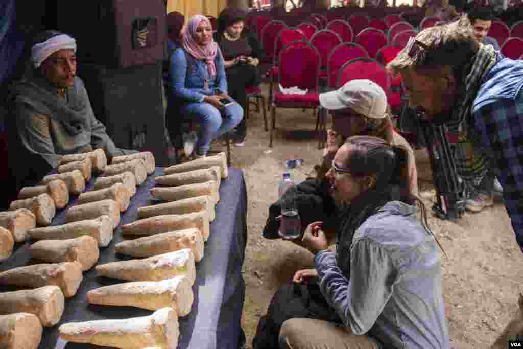 Tourists look at 100 funerary cones on display found in the tomb of Kampp 150 in the Draa Abul Naga necropolis on Luxor’s west bank, Egypt, Dec. 9, 2017. Such cones were generally placed on outer walls of tombs, above the entrance. (H. Elrasam/VOA)