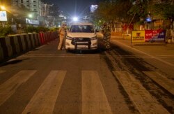 An Indian police, left, and a paramilitary personnel stop a vehicle during a complete lockdown amid growing concerns of coronavirus in Gauhati, India, Tuesday, March 24, 2020.