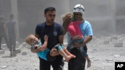 This photo provided by the Syrian Civil Defense group known as the White Helmets shows civil defense workers carrying children after airstrikes hit a school housing a number of displaced people, in the western part of the southern Deraa province of Syria, June 14, 2017.