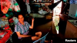 ស្រ្តី​ម្នាក់​នេះ យោល​អង្រឹង​កូន​នៅ​ក្នុង​ហាង​លក់​ទំនិញ​របស់​គាត់​ដែល​លិច​ទឹក​ នៅ​ក្នុង​ខេត្ត​កណ្តាល​នៃ​ប្រទេស​កម្ពុជា នៅ​ខែតុលា ឆ្នាំ២០១៣។