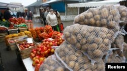FILE - People walk past goods at the market in Suwalki, Poland.