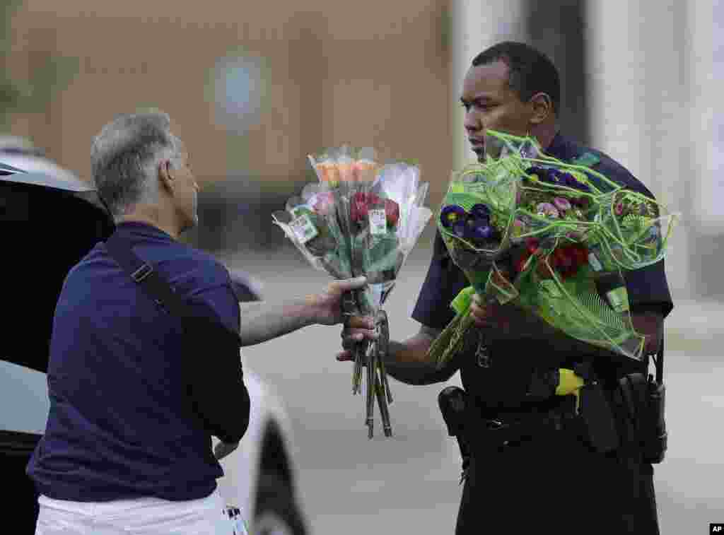 A Dallas police officer receives flowers at a roadblock outside their headquarters, July 9, 2016.