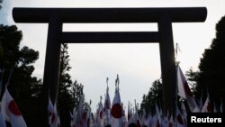FILE - Members of nationalist movement "Ganbare Nippon" raise Japanese national flags towards the huge Torii gate at the Yasukuni shrine.