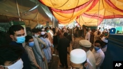 People stand outside a government office to get their identity cards verified to receive aid from the government during a nationwide lockdown to try to contain the outbreak of the coronavirus, in Peshawar, Pakistan, June 16, 2020. 