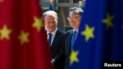FILE - European Council President Donald Tusk and Chinese Premier Li Keqiang arrive to attend an EU-China Summit in Brussels, Belgium, June 2, 2017.