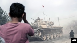 2016年8月25日，在土耳其，一个男孩看着土耳其军队坦克和装甲运输车跨过国界驶向叙利亚。