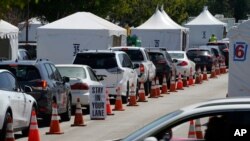 FILE - Motorists are inside their vehicles as they wait their turn to be inoculated with a COVID-19 vaccine at the California State University, Los Angeles campus in Los Angeles, April 8, 2021. 