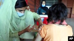 FILE - A woman receives the Pfizer COVID-19 vaccine from a health worker at a vaccination center in Islamabad, Pakistan, Oct. 4, 2021.