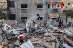 Palestinians check the damage amid the rubble of a destroyed building on the first day of the Eid al-Fitr holiday, following Israeli airstrikes on the northern Gaza Strip town of Beit Lahia, early on May 13, 2021.