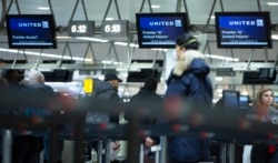 A man wears a protective mask as he waits to check into a flight to the United States in the main terminal of Brussels International Airport in Brussels, Friday, March 13, 2020.