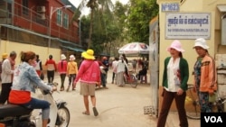 កម្មករ​កាត់ដេរ​ខ្មែរ​ឈរ​នៅ​ខាងក្រៅ​ក្រុមហ៊ុន​អឹមវ៉េ (M&V) កាត់ដេរ​អន្តរជាតិ នៅ​ថ្ងៃទី ៨ ខែតុលា ឆ្នាំ២០១៥។ (ឡេង ឡែន/VOA) 